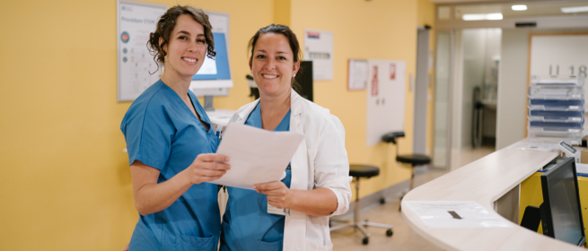 Photo d'une soignante et d'un médecin tout sourire avec un dossier patient en mains